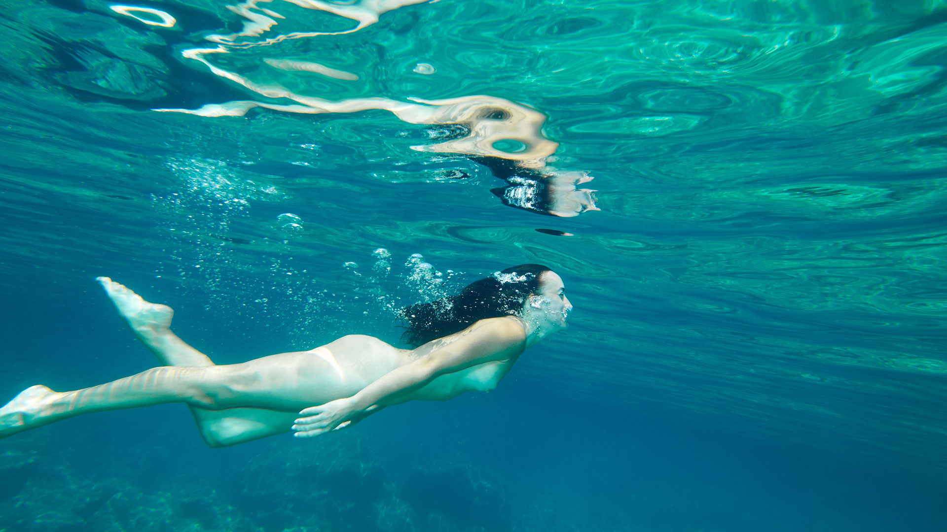 Femme nue sous nageant sous l'eau